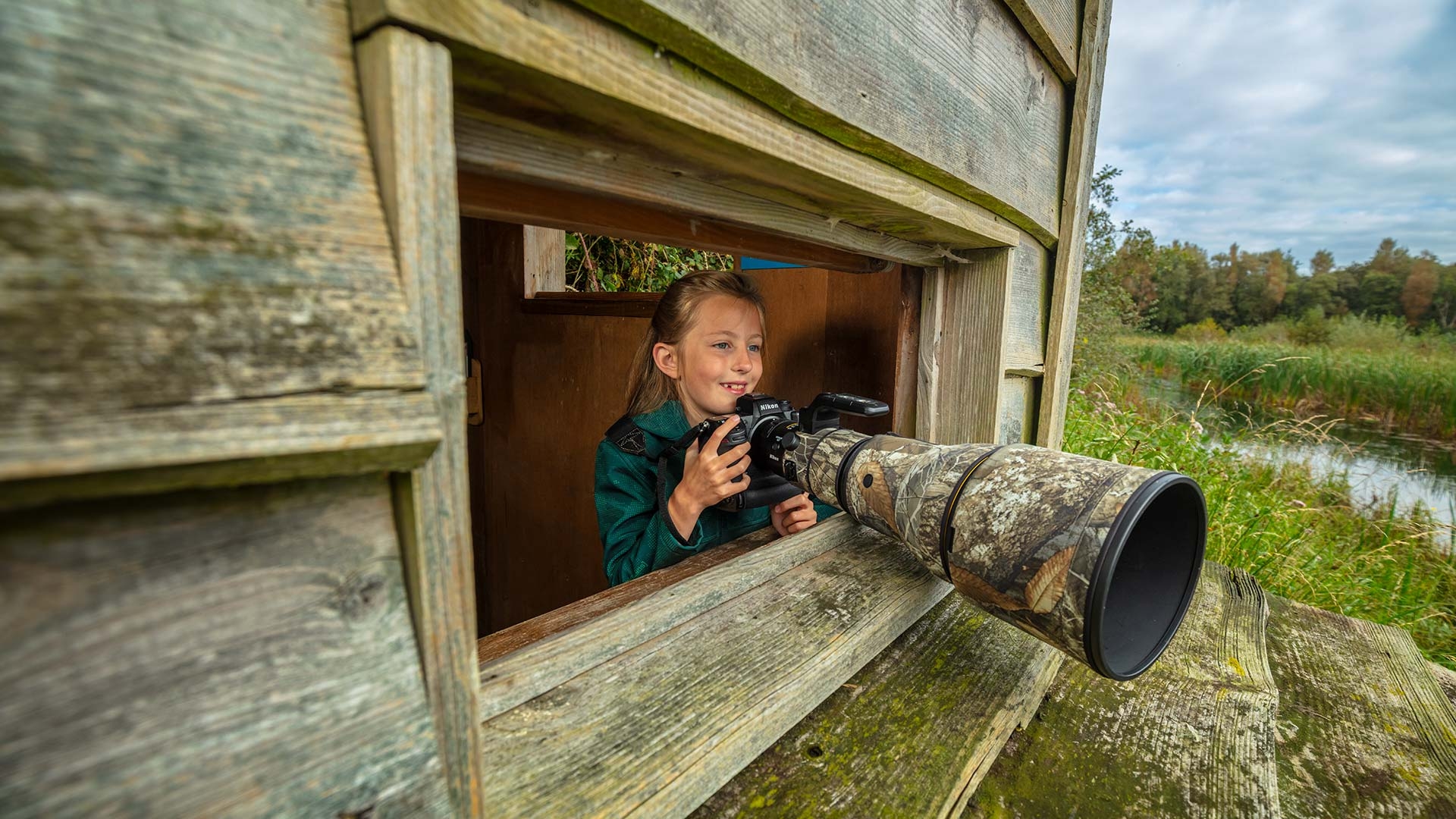 A girl uses a camera from a hide
